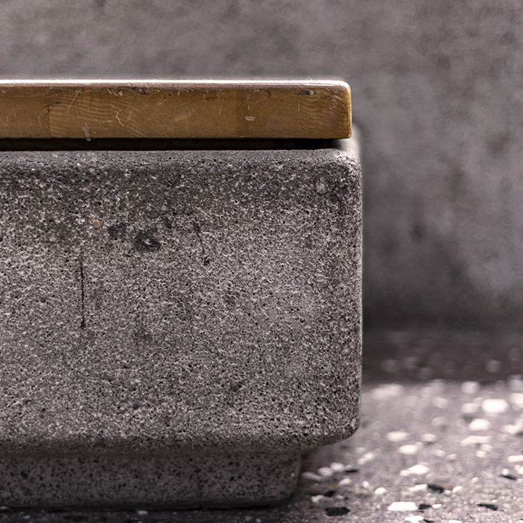 A macro shot showing the gritty texture of a grey stone base topped with a smooth wooden surface.